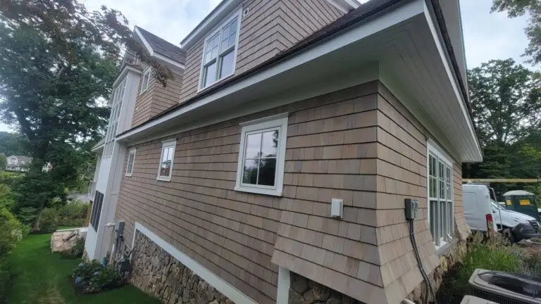 a house with a stone wall and shake siding