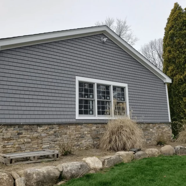 a house with a stone wall and new vinyl siding