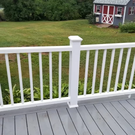 a deck with a white railing and a lawn and a shed